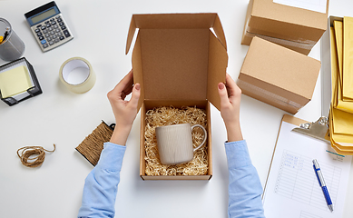 Image showing hands packing mug to parcel box at post office