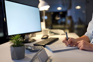 Image showing businesswoman writing to notebook at night office