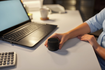 Image showing hand using smart speaker at night office