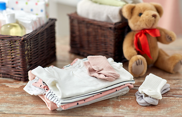 Image showing baby clothes and teddy bear toy on table at home