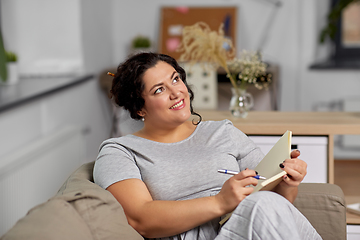 Image showing happy young woman with diary on sofa at home