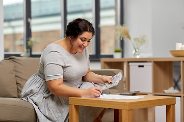 Image showing woman with money, papers and calculator at home