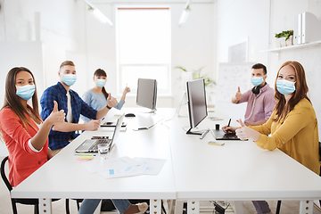 Image showing business team in medical masks showing thumbs up