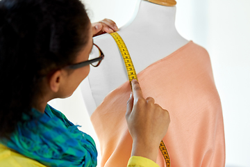 Image showing fashion designer measuring dress with tape measure