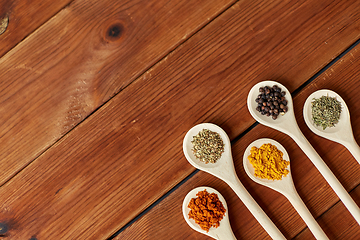 Image showing spoons with different spices on wooden table