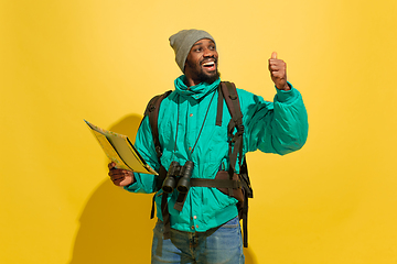 Image showing Full length portrait of a cheerful young african tourist guy isolated on yellow background