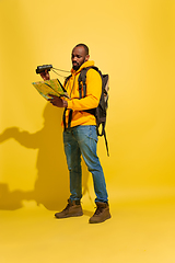 Image showing Full length portrait of a cheerful young african tourist guy isolated on yellow background
