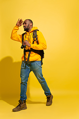 Image showing Full length portrait of a cheerful young african tourist guy isolated on yellow background