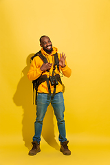 Image showing Full length portrait of a cheerful young african tourist guy isolated on yellow background