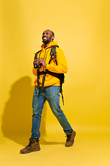 Image showing Full length portrait of a cheerful young african tourist guy isolated on yellow background