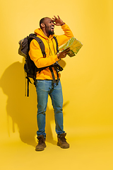 Image showing Full length portrait of a cheerful young african tourist guy isolated on yellow background