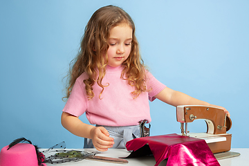 Image showing Little girl dreaming about future profession of seamstress