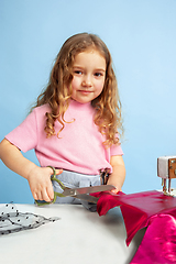 Image showing Little girl dreaming about future profession of seamstress