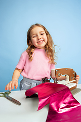 Image showing Little girl dreaming about future profession of seamstress