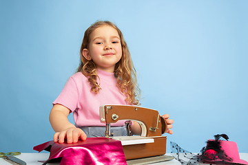 Image showing Little girl dreaming about future profession of seamstress