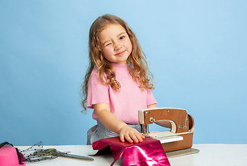 Image showing Little girl dreaming about future profession of seamstress