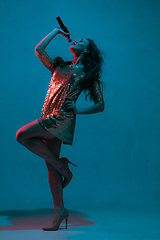 Image showing Caucasian female singer portrait isolated on blue studio background in neon light