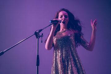 Image showing Caucasian female singer portrait isolated on purple studio background in neon light