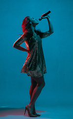 Image showing Caucasian female singer portrait isolated on blue studio background in neon light