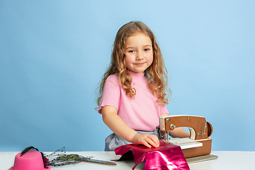 Image showing Little girl dreaming about future profession of seamstress