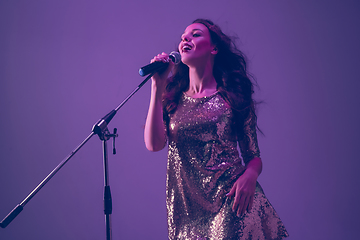 Image showing Caucasian female singer portrait isolated on purple studio background in neon light