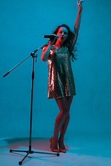 Image showing Caucasian female singer portrait isolated on blue studio background in neon light