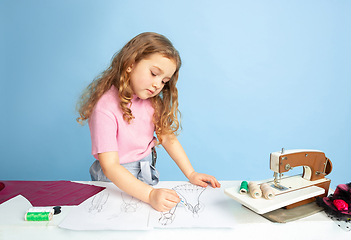 Image showing Little girl dreaming about future profession of seamstress