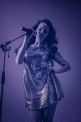 Image showing Caucasian female singer portrait isolated on purple studio background in neon light