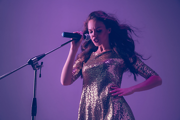 Image showing Caucasian female singer portrait isolated on purple studio background in neon light