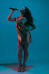 Image showing Caucasian female singer portrait isolated on blue studio background in neon light