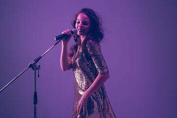 Image showing Caucasian female singer portrait isolated on purple studio background in neon light