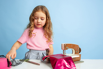 Image showing Little girl dreaming about future profession of seamstress