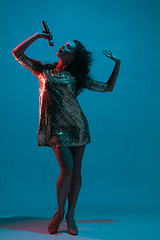 Image showing Caucasian female singer portrait isolated on blue studio background in neon light