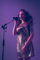 Image showing Caucasian female singer portrait isolated on purple studio background in neon light