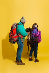 Image showing Portrait of a cheerful young tourist couple isolated on yellow background