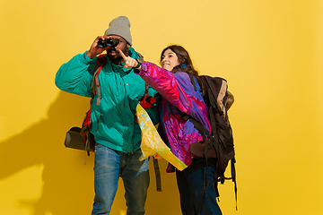 Image showing Portrait of a cheerful young tourist couple isolated on yellow background