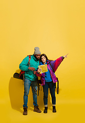 Image showing Portrait of a cheerful young tourist couple isolated on yellow background