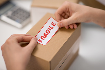 Image showing woman sticking fragile mark to parcel box