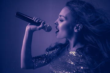 Image showing Caucasian female singer portrait isolated on purple studio background in neon light