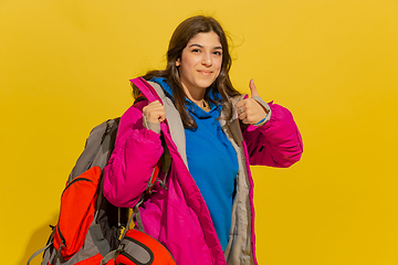 Image showing Portrait of a cheerful young caucasian tourist girl isolated on yellow background