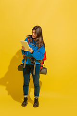 Image showing Full length portrait of a cheerful young caucasian tourist girl isolated on yellow background