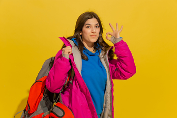 Image showing Portrait of a cheerful young caucasian tourist girl isolated on yellow background