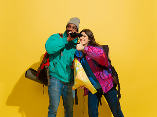 Image showing Portrait of a cheerful young tourist couple isolated on yellow background