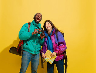 Image showing Portrait of a cheerful young tourist couple isolated on yellow background