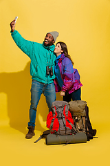 Image showing Portrait of a cheerful young tourist couple isolated on yellow background