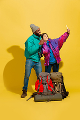 Image showing Portrait of a cheerful young tourist couple isolated on yellow background