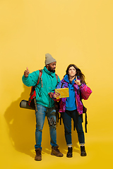 Image showing Portrait of a cheerful young tourist couple isolated on yellow background