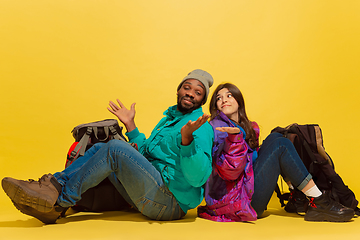 Image showing Portrait of a cheerful young tourist couple isolated on yellow background