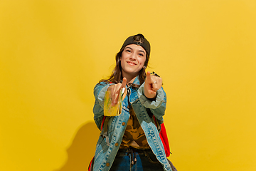 Image showing Portrait of a cheerful young caucasian tourist girl isolated on yellow background