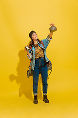 Image showing Portrait of a cheerful young caucasian tourist girl isolated on yellow background